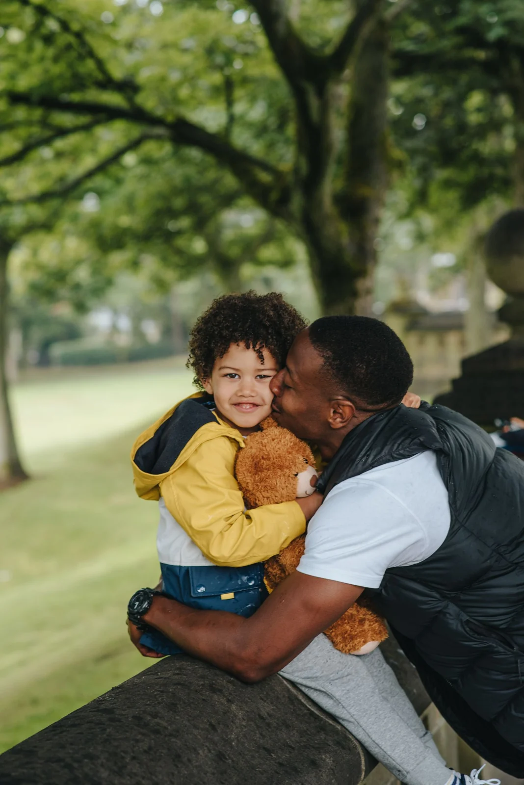 A smiling father hugging his young son outdoors.